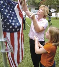Donna Ginther, the widow of Navy Seabee Ron Ginther who died in May while serving in Iraq, and her daughter Alayna, 9, raise the American flag during a dedication on Saturday for the new flag pole recently placed in the family's front yard by Navy Seabee Vetrans of America, Island X-2. 08/07/04 Paul Crate/News Chief. Donna Ginther, the widow of Navy Seabee Ron Ginther who died in May while serving in Iraq, and her daughter Alayna, 9, raise the American flag during a dedication on Saturday for the new flag pole recently placed in the family's front yard by Navy Seabee Vetrans of America, Island X-2. 08/07/04 Paul Crate/News Chief.